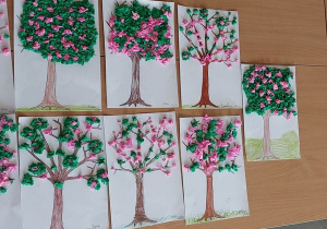 Prace dzieci przedstawiające kwitnące wiosenne drzewa.