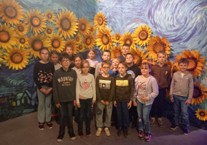 Uczniowie w galerii obrazów na tle słoneczników