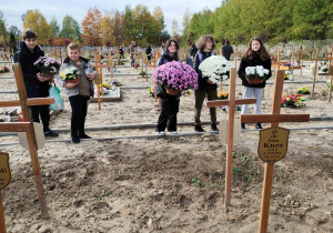 Uczniowie przygotowują się do ustawienia kwiatów na grobach.