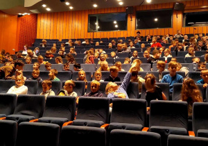 Dzieci zajmują miejsca w teatrze.