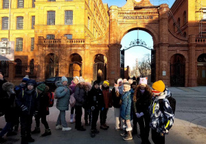 Uczniowie przed bramą fabryki Izraela Poznańskiego.